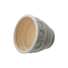 Cream ceramic planter with open top showing interior glaze and wave embossing