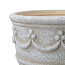 Cream ceramic planter close-up with wave band and embossed bow motifs