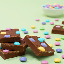 Milk chocolate pieces with pastel candy-coated bits scattered on surface