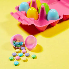 Egg-shaped pastel candies in a carton, with small candy pieces around