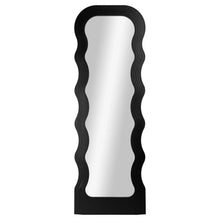 Full view of tall floor mirror with black wavy frame and arched top