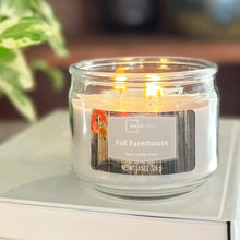 Lit scented candle in clear glass jar with Fall Farmhouse label