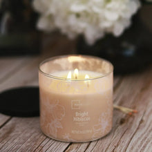 Glass jar scented candle with Bright Hibiscus label, glowing three wicks