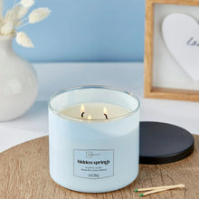 Light blue 3-wick scented candle with three flames in glass jar