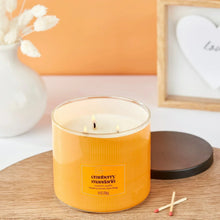 Three-wick cranberry mandarin candle in amber jar, wicks lit on table