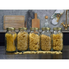 Glass pantry jars with gold lids, filled with assorted dry foods and pasta