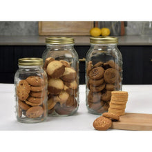 Glass pantry jars with gold lids, filled with cookies; cookie stack beside jars
