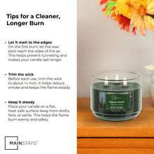 Green 3-wick scented candle in clear glass jar, Alpine Forest label, lit