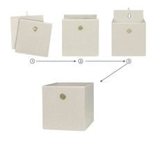 Beige fabric cube storage bin with gold grommet handle, folding panels shown