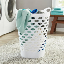 White perforated laundry hamper holding folded towels on a floor