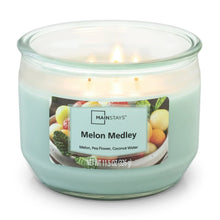 Candle jar with three burning wicks, teal wax, and Melon Medley label