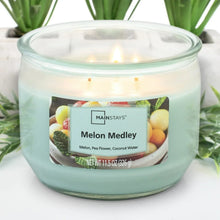 Teal wax three-wick candle in clear glass jar with Melon Medley label