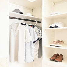 White plastic hangers holding shirts on a closet rod