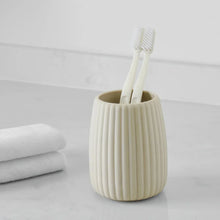 Beige ribbed rubberized plastic toothbrush holder holding a toothbrush