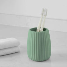 Green ribbed toothbrush holder holding a toothbrush, counter-ready design