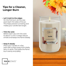 Vanilla scented glass jar candle with lit wick in clear glass jar