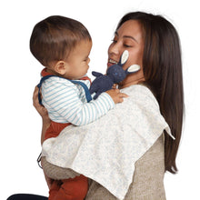 Plush bunny rattle held near baby face, with light patterned burp cloth