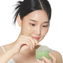 Woman applying green cheek patch gel from a small jar to her cheek