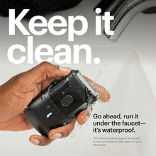 Black foil face shaver held in hand with water droplets on the head