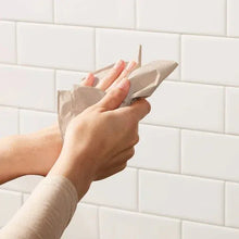 Brown 1-ply recycled paper towel being pulled by hands on a wall