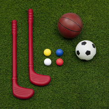 Red plastic hockey sticks with soccer and ball accessories on grass