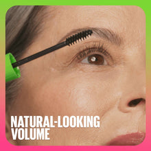 Black mascara applied to upper lashes with green-handled wand near eye