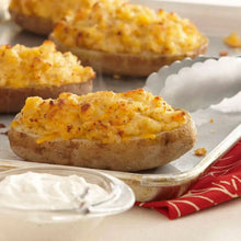 Seasoned garlic topping over sliced baked potatoes on a tray with a small sauce cup