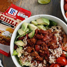 Bowl of chili with diced onions and avocado, plus seasoning mix box