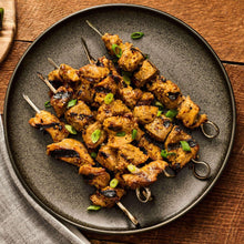 Grilled pork kabobs with pineapple teriyaki seasoning in a skillet bowl with green onions