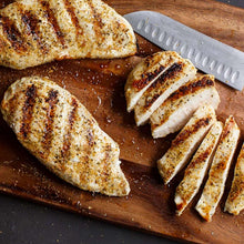 Sliced grilled chicken breasts on a wooden cutting board
