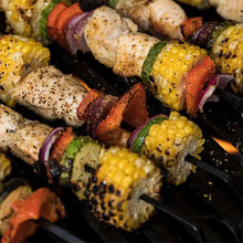 Grilled chicken and vegetable skewers with seasoning on a barbecue grill