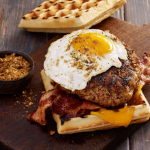 Open-faced breakfast toast with fried egg, melted cheese, bacon, and spice crumbs