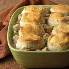 Seasoned chicken topped with baked bread rolls in green bowl