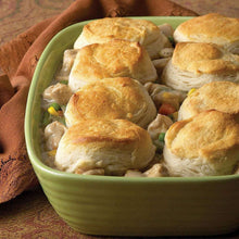 Poultry gravy with vegetables and golden biscuits in a green casserole dish