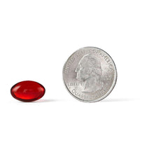 Red omega-3 krill oil softgel next to quarter coin for size