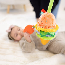 Infant playing with clip-on ice cream plush toy with peach scoop and orange teether