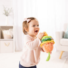 Infant holding ice cream clip-on plush toy with peach scoop and stacked colored layers