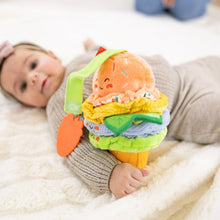 Ice cream clip-on plush toy held by an infant, with green ribbon and stacked layers