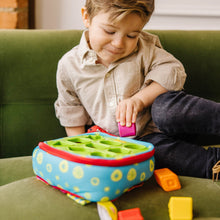 Baby playing with round Take-Along shape sorter on table with colorful blocks
