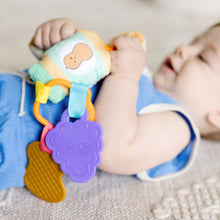 Baby grasping clip-on sensory toy with purple flower fabric tag and waffle heart charm