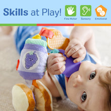 Soft fabric cube clip-on toy with purple flower patch, held by baby hands