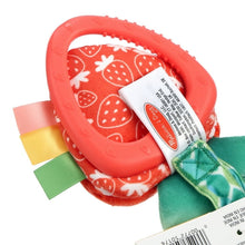 Red teether ring with patterned fabric and woven tag, green leaf detail