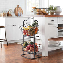 3-tier standing black wire basket with curved handle, holding assorted kitchen items
