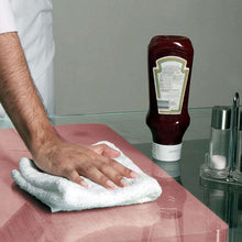 White cotton terry towel being used to wipe a pink countertop surface.