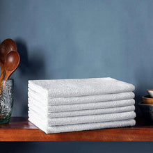 Stack of white cotton terry towels on a surface, folded edges visible.