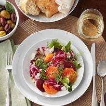 White porcelain bowl filled with salad greens and fruit slices