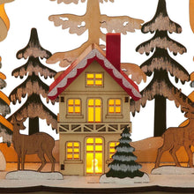 Lit house ornament with red roof, glowing windows, and surrounding pine trees