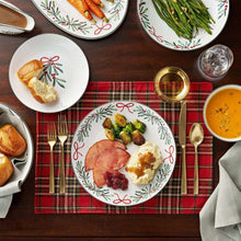 Porcelain holiday plates and bowls with bow-and-leaf trim on a table setting