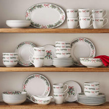 Porcelain holiday dinnerware with bow and leaf accents, plates and mugs arranged on shelf