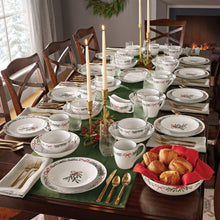 Porcelain holiday dinnerware set with bow and leaf pattern, plates, bowls, and mugs on table